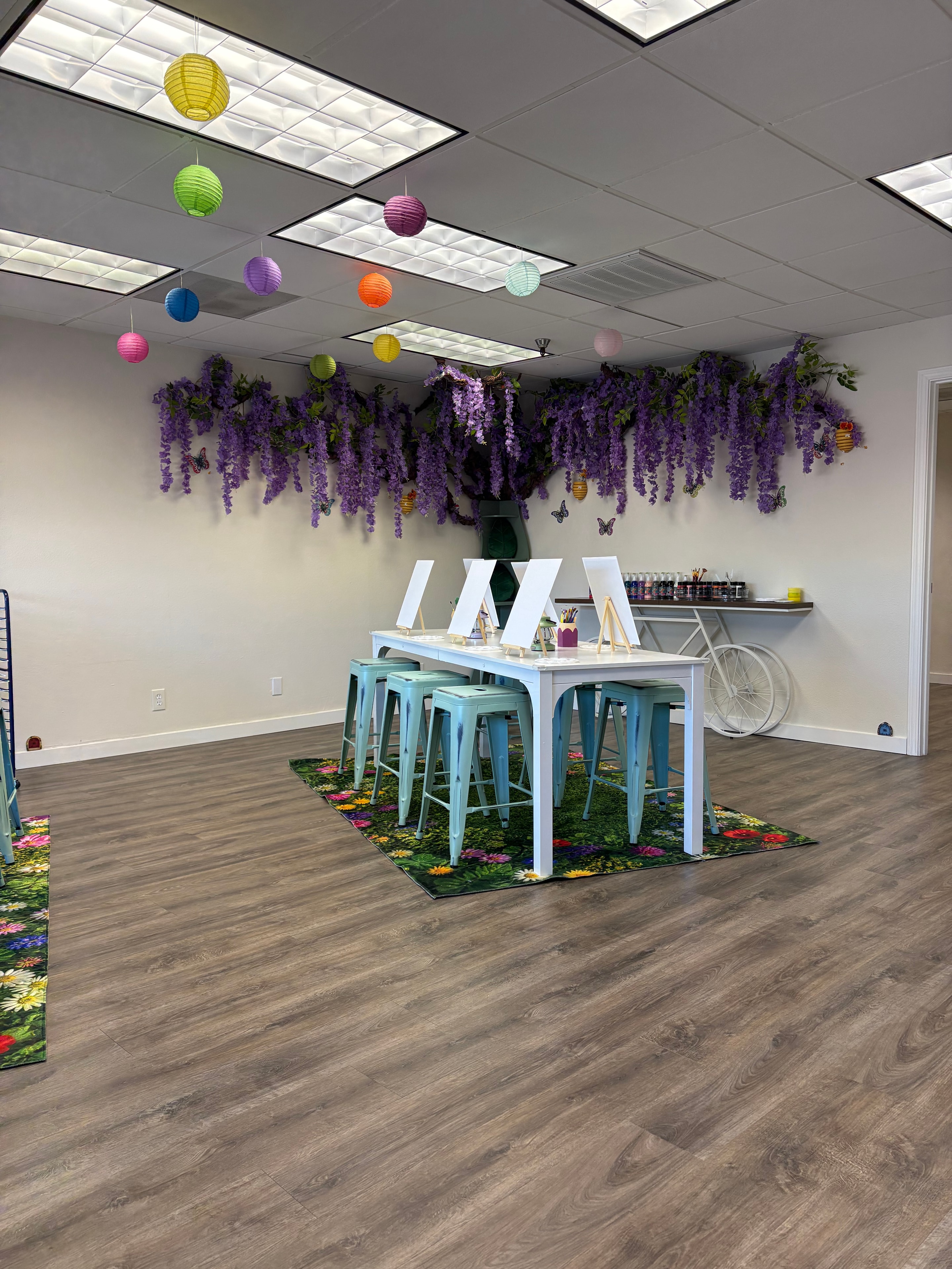 Studio interior with purple wisteria, colorful lanterns, and teal stools