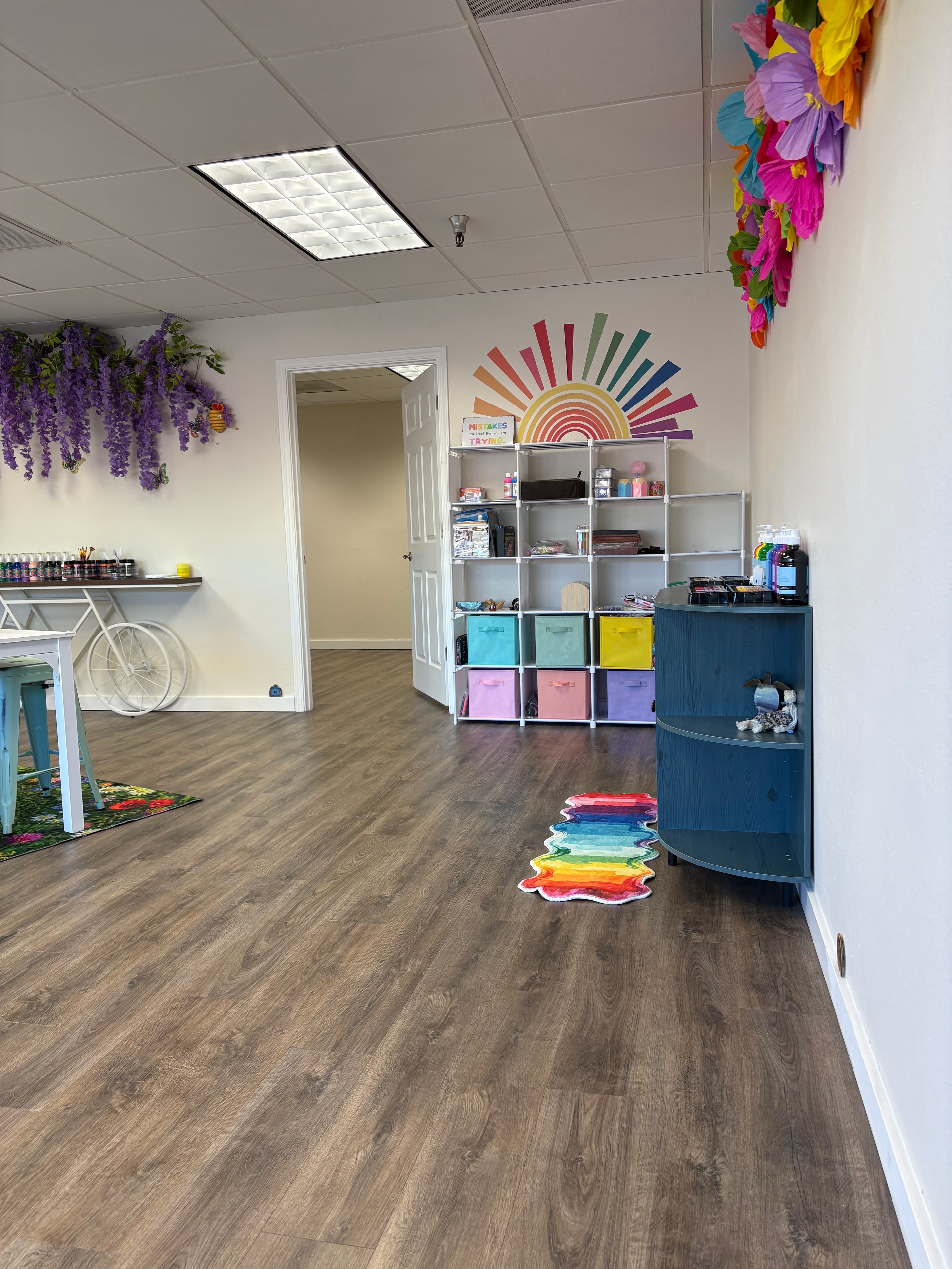 Studio with rainbow sun wall art, colorful cube shelving, and wisteria decor