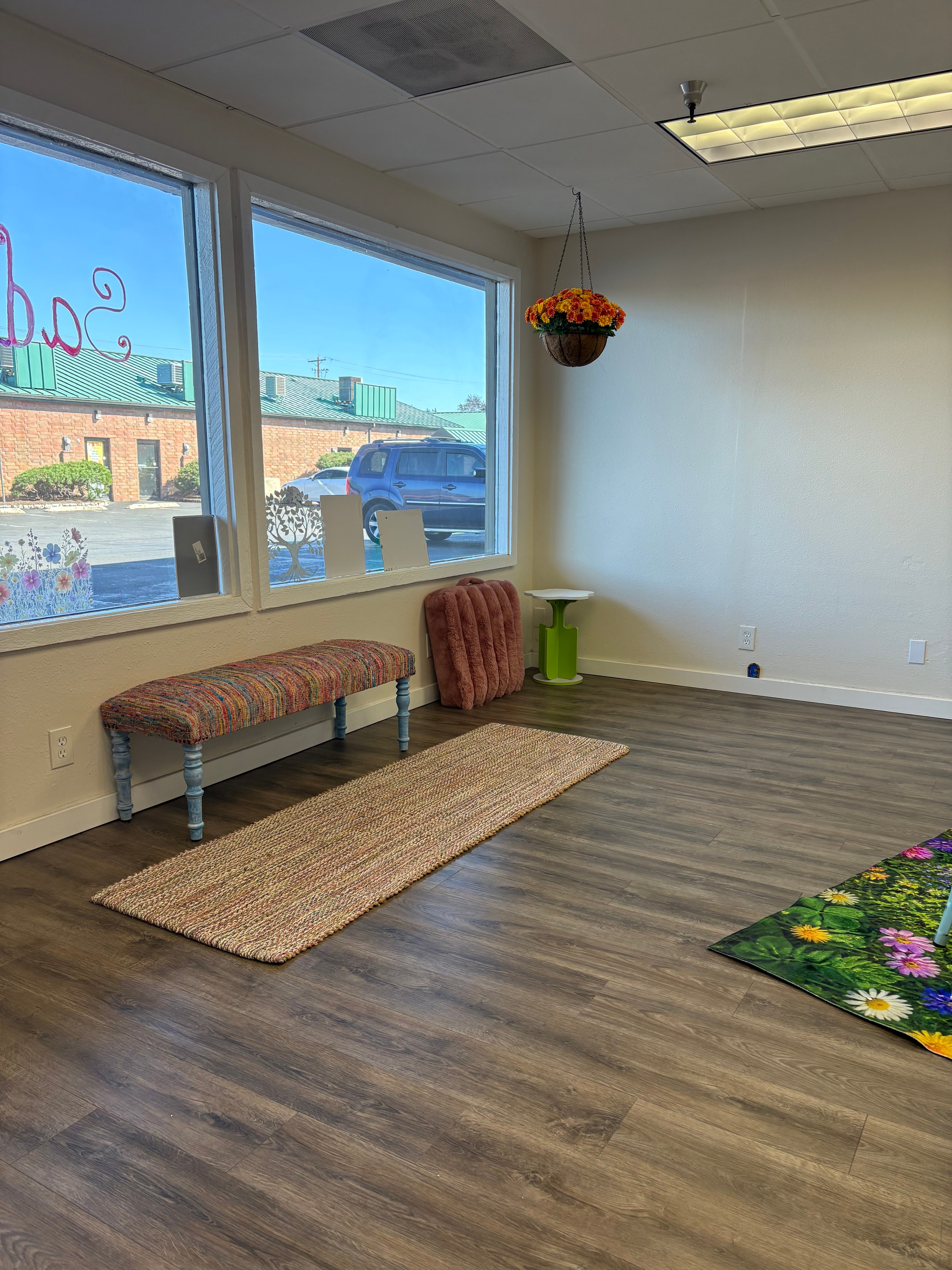 Studio waiting area with large windows, bench seating, and floral decor